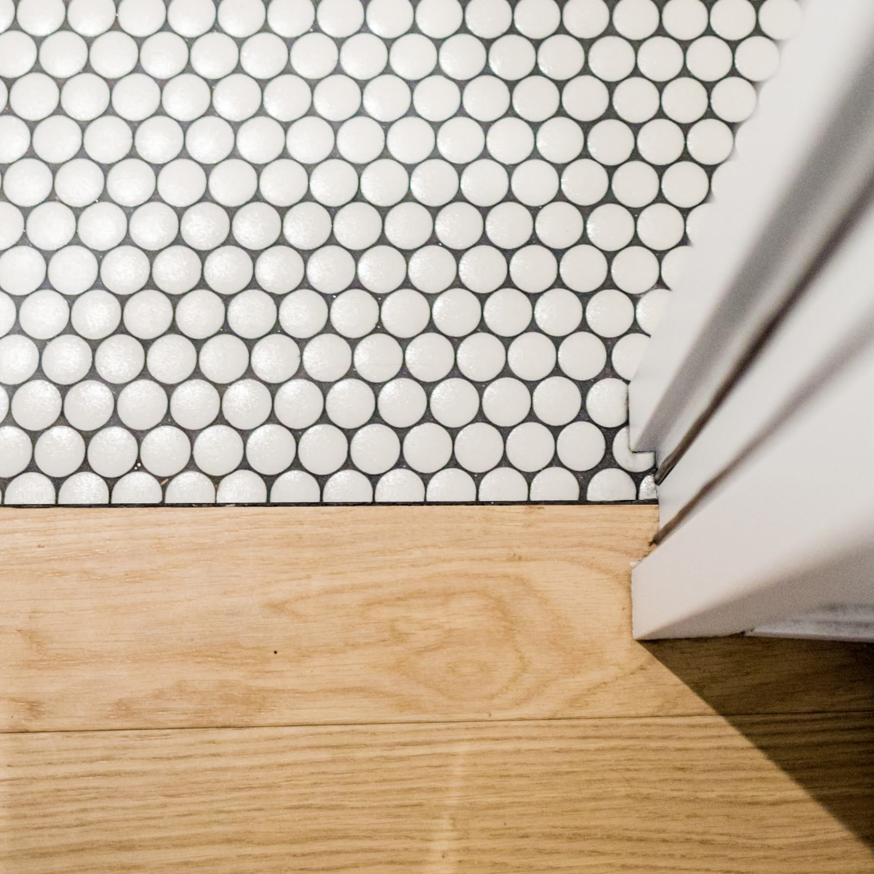 Jonction mosaïque pastilles blanches et parquet chêne clair